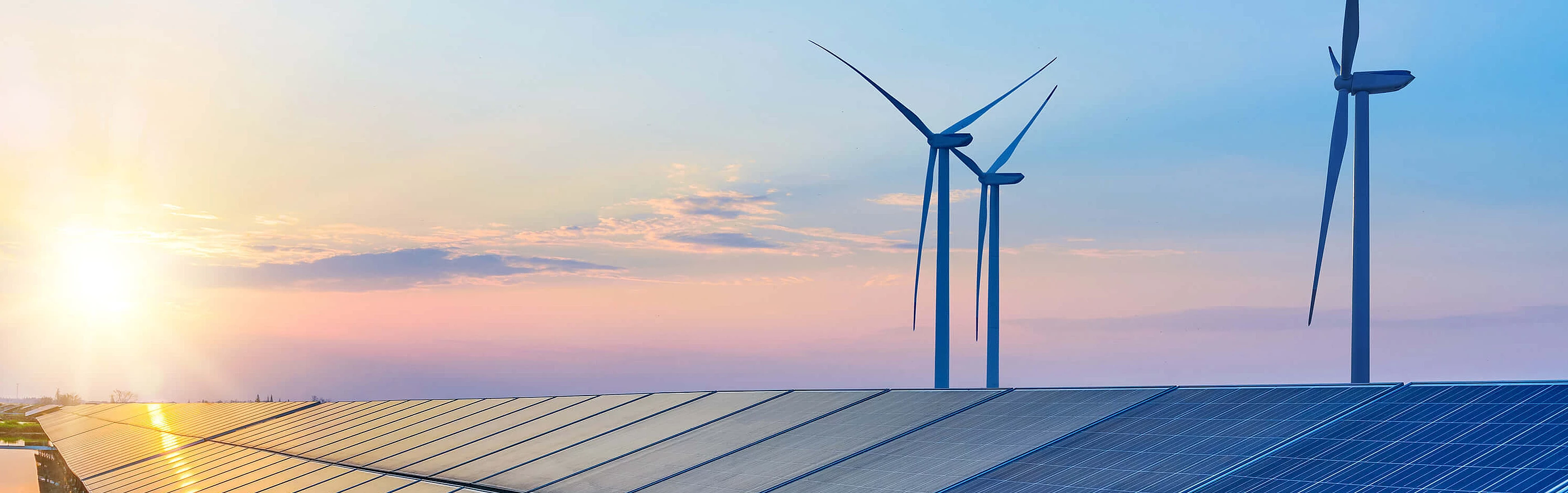 Solarpanele mit Windrädern und Sonnenuntergang im Hintergrund