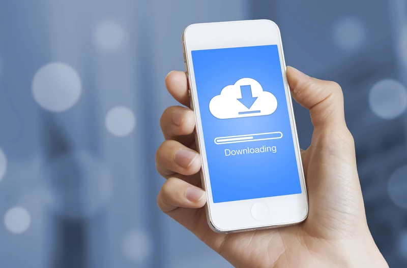 Hand holding a cell phone with something being downloaded onto it