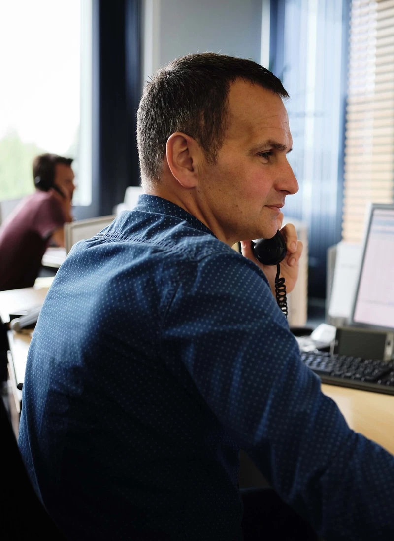 Employee talking on the phone at a desk with screens